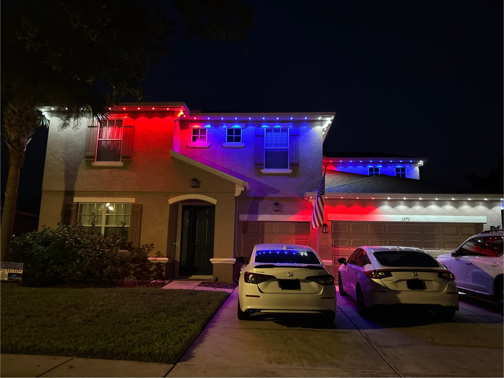 Stucco two-story home lit in red, white and blue permanent LEDs