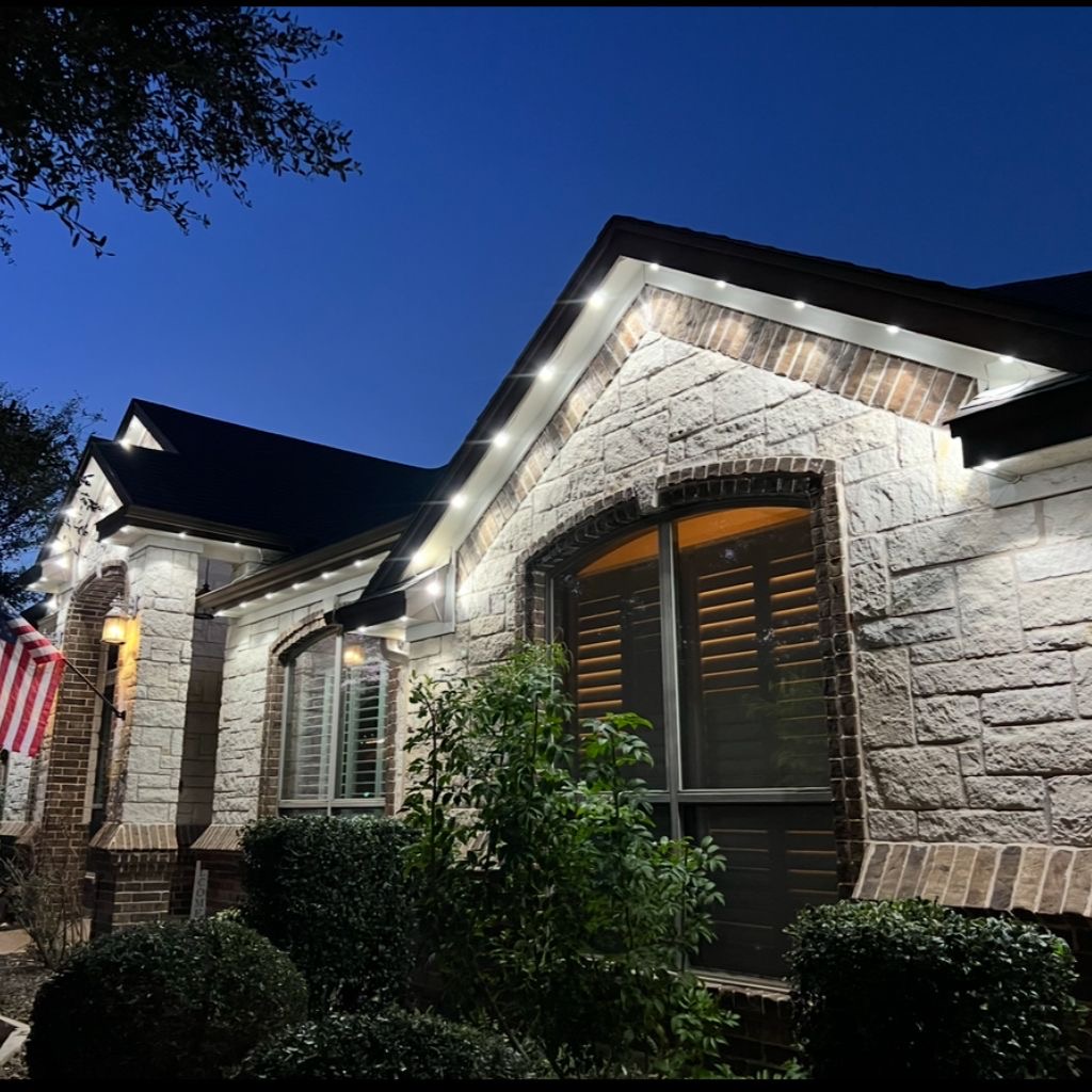 Stone home with clean warm white permanent LED accent lighting at dusk