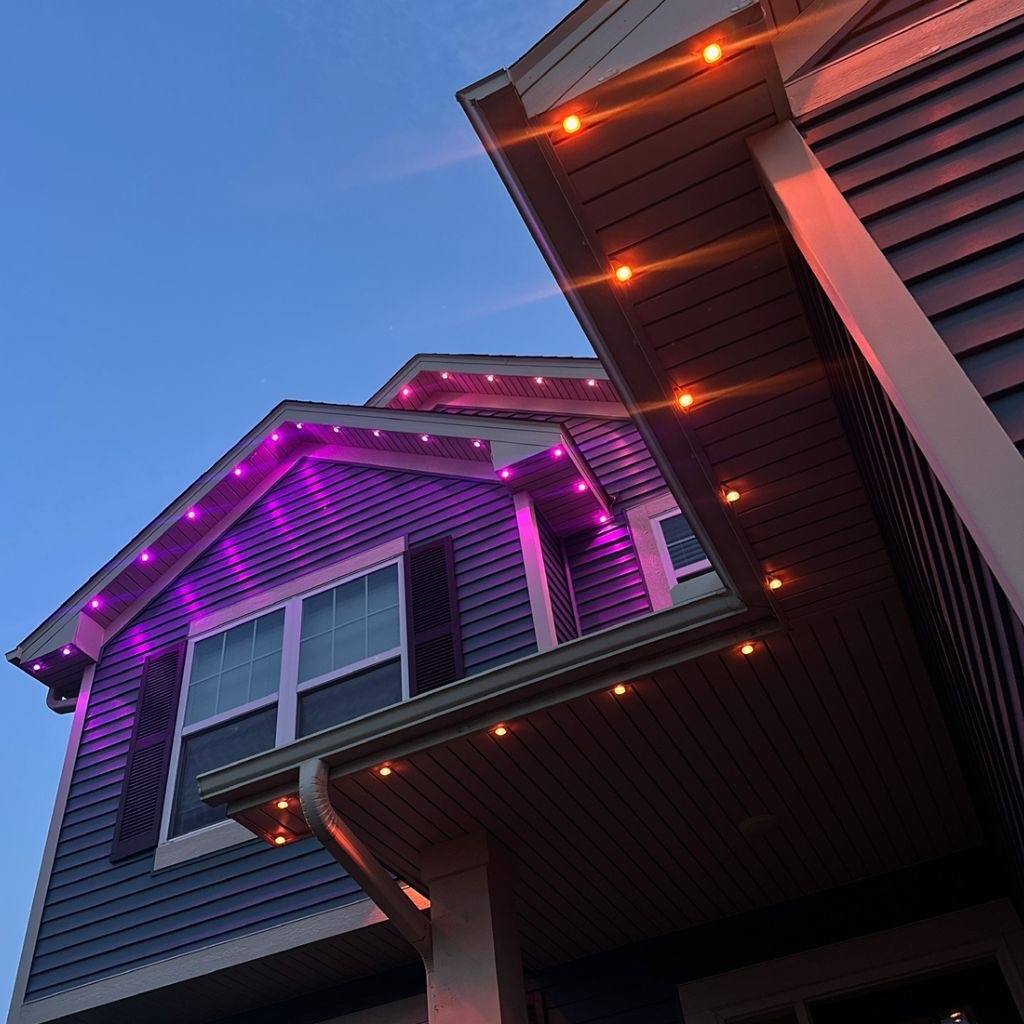 Close-up of purple and amber permanent LED lights along a gable and soffit